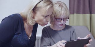 母亲和她的儿子在数码平板电脑上玩慢动作素材视频