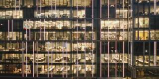鸟瞰图的现代办公室在玻璃摩天楼在晚上，全景左边。