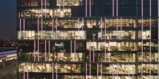 俯瞰摩天大楼的办公室和工作到很晚的人，办公室的窗户被照亮在商业中心大楼的立面上。