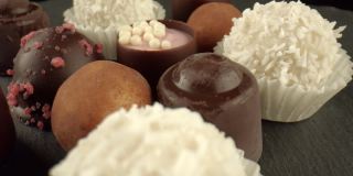 巧克力、华夫饼、杏仁蛋白软糖和各种馅料放在黑色的桌子表面。糖含量高的糖果制品。