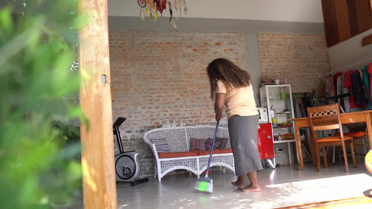 成熟的女人打扫地毯和房子