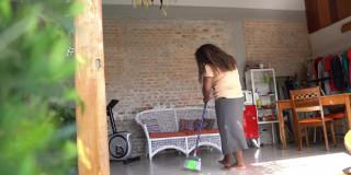 成熟的女人打扫地毯和房子