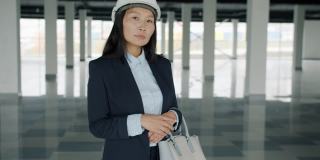 亚洲年轻女士的慢动作肖像建筑投资者站在新大楼戴着头盔