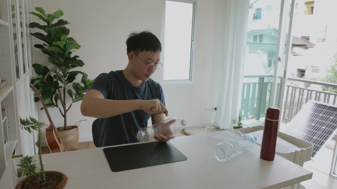 一名亚洲男子正在制作一个可回收的塑料瓶，用于拍摄植物储存视频