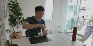一名亚洲男子正在制作一个可回收的塑料瓶，用于拍摄植物储存视频