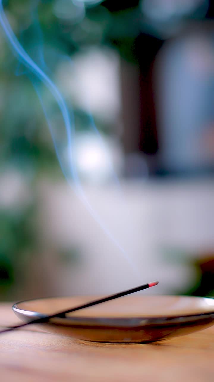 垂直视频。房间里的桌子上放着一根香薰和冥想棒，烟从里面冒出来