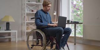 一个坐在轮椅上专注的聪明人，在网上发短信，在笔记本电脑键盘上打字，思考。集中自信的白人残疾人在家里客厅上网。