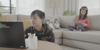 亚洲十多岁的男孩在家用笔记本电脑视频通话，使用zoom在线虚拟课堂，孩子们在家上学，新冠疫情期间远程学习，新常态概念