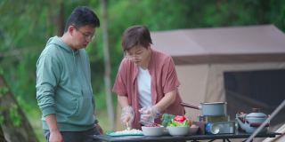 周末早上，亚洲华人夫妇在露营帐篷旁准备早餐