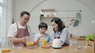 一个亚洲家庭，爸爸妈妈和儿子在厨房帮忙做饭做冰沙视频素材模板下载
