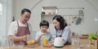 一个亚洲家庭，爸爸妈妈和儿子在厨房帮忙做饭做冰沙