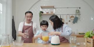 一个亚洲家庭，爸爸妈妈和儿子在厨房帮忙做饭做冰沙