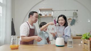 一个亚洲家庭，爸爸妈妈和儿子在厨房帮忙做饭做冰沙视频素材模板下载