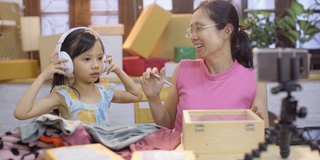 女儿用智能手机帮助妈妈在网上卖衣服。亚洲自由职业女性开始在社交媒体上销售新业务，女孩在家工作