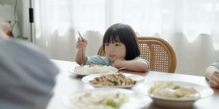 亚洲幸福家庭一起用餐具做活动。一个男孩自己用勺子吃米饭。家庭关系
