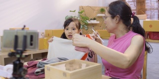 小企业主和她的孩子用手机在社交媒体上卖衣服和衣服