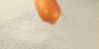 超级慢动作在一堆面粉中落下一个新鲜的鸡蛋。在高速相机拍摄1000帧每秒。