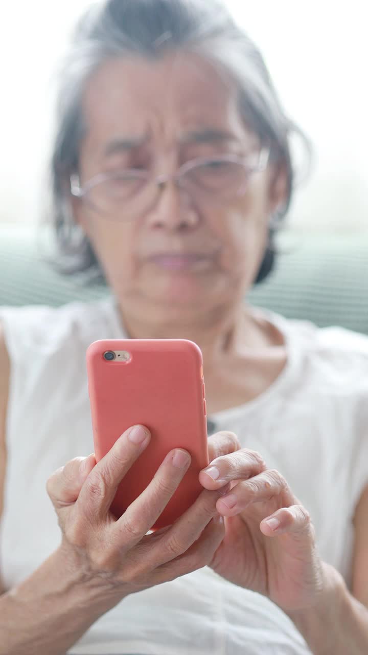 亚洲老妇人在客厅玩智能手机