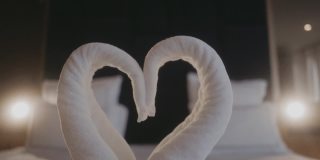 在浪漫的酒店房间床上叠成天鹅形的毛巾