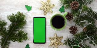 绿屏技术手机在圣诞装饰桌上俯视图平放，模拟空间为复制文字，智能手机色度键，新年在线概念无人