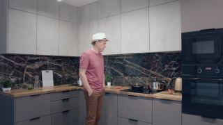 一个戴着帽子的年轻人一边做饭一边在厨房里唱歌跳舞视频素材模板下载