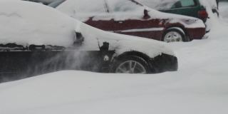 冬天。停着的汽车都被雪覆盖了。刮着大风。慢动作的降雪。交通状况不佳，暴风雪。交通事故的危险。十字路口