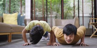 亚洲父亲和儿子在家里一起做俯卧撑。