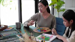 年轻的亚洲老师在美术课上和亚洲女孩一起画画。视频素材模板下载