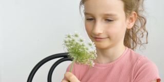 小女孩坐在家里，手里拿着花在夏天的时间和打喷嚏，过敏，哮喘，或过敏的概念