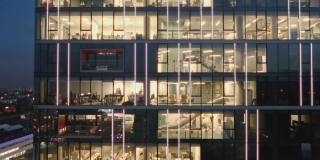 俯瞰现代摩天大楼办公室的夜景，商人们工作到很晚。