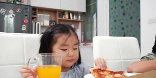 快乐的亚洲女孩喜欢在假期的午餐时间在家吃披萨