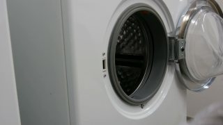 男人用手把洗好的衣服放进洗衣机。洗衣房有一台白色的大洗衣机。视频素材模板下载
