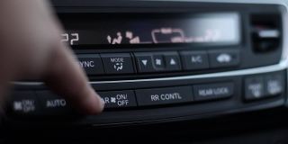 一根手指按下气候控制按钮。这个人使车里的温度变暖或变冷。