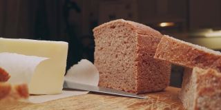 农场面包和黄油躺在厨房的木板上。早餐切成的酸面包片。移动滑块极端接近股票镜头