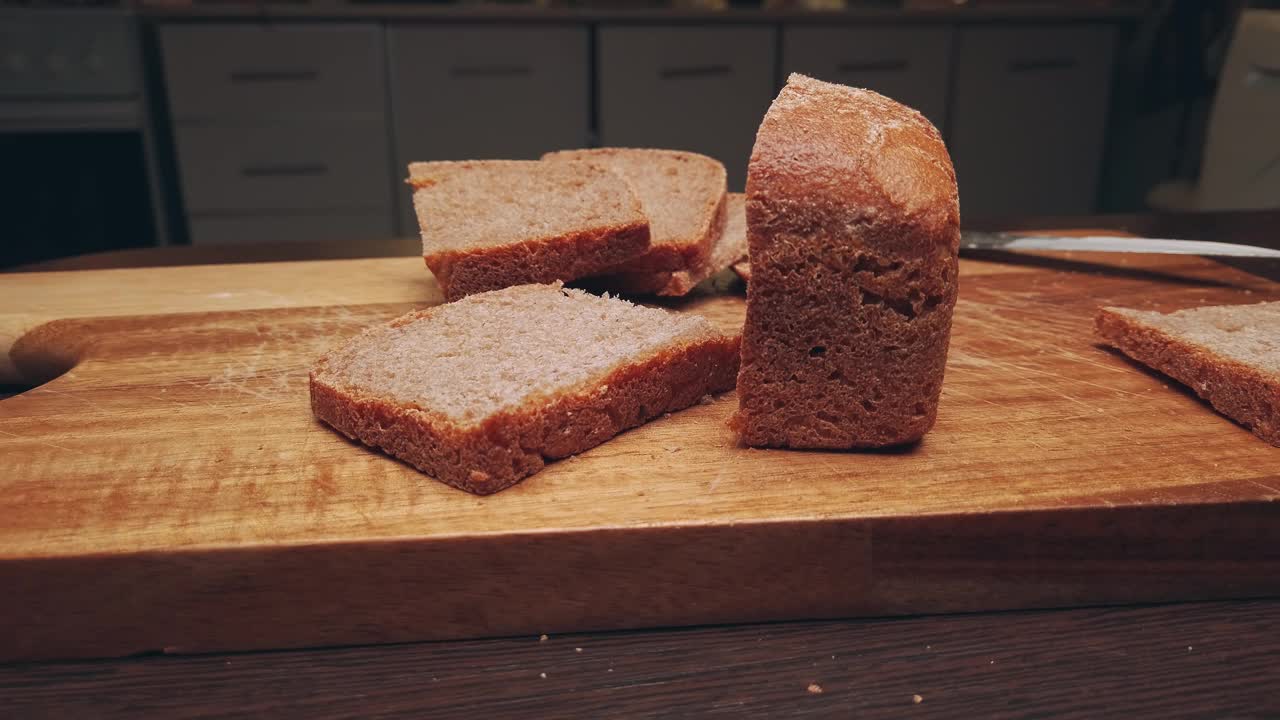 农场面包躺在厨房的一块木板上。早餐切成的酸面包片。移动滑块极端接近股票镜头