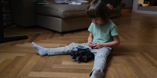 幼儿在地板上检查遥控玩具车