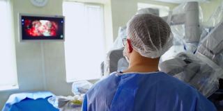 医生用外科手术看着监视器。医院里有一个医疗机器人做现代外科手术。后面的观点。