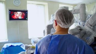医生用外科手术看着监视器。医院里有一个医疗机器人做现代外科手术。后面的观点。视频素材模板下载