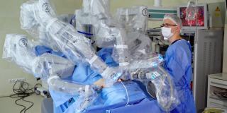 外科手术用高科技设备。手术机器人为病人进行微创手术。医院里穿着医疗制服的专业外科医生在机器人旁边。