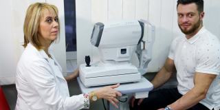 眼科医生和门诊病人。女医生在眼科办公室用现代仪器为病人检查视力。