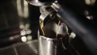 将美式咖啡或浓咖啡从专业的咖啡机倒进咖啡杯。早上烤黑咖啡视频素材模板下载