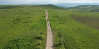 一条山间公路的俯视图。无人机拍摄的一条蜿蜒的道路穿过绿色的山丘和山脉。