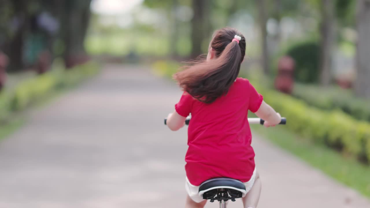 快乐的亚洲女孩在公园里骑自行车