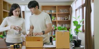 年轻企业家创业，亚洲夫妇包装产品纸箱或包裹运输到客户