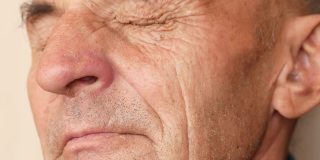 肖像中的一个沉思和pechao老人经常眨着疲倦的皱纹的眼睛。老年视力问题。白人退休老人的特写镜头。有选择性的重点