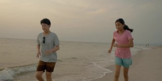 亚洲儿童在沙滩上奔跑，伴以日出为背景，积极的生活理念。