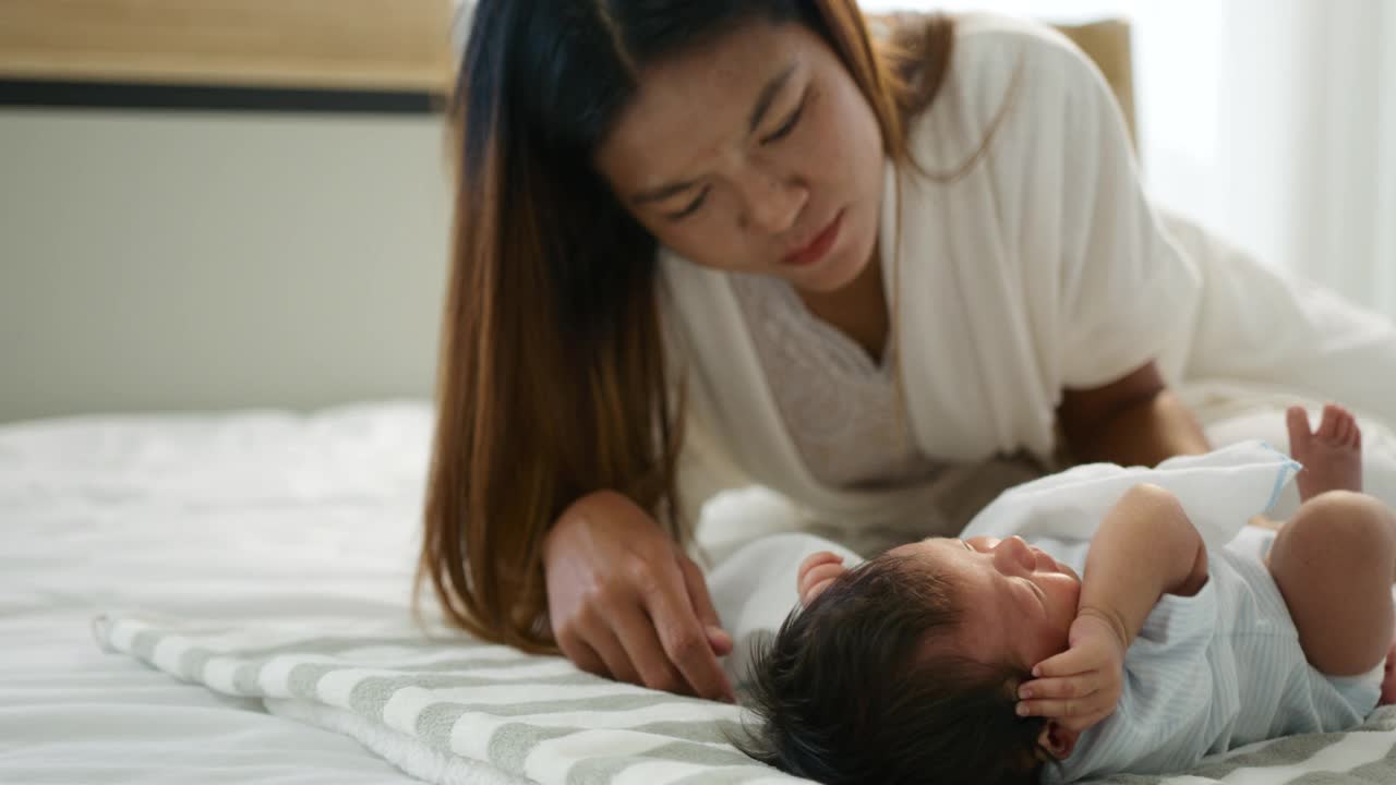 母亲在家里的卧室里给新生婴儿喂奶