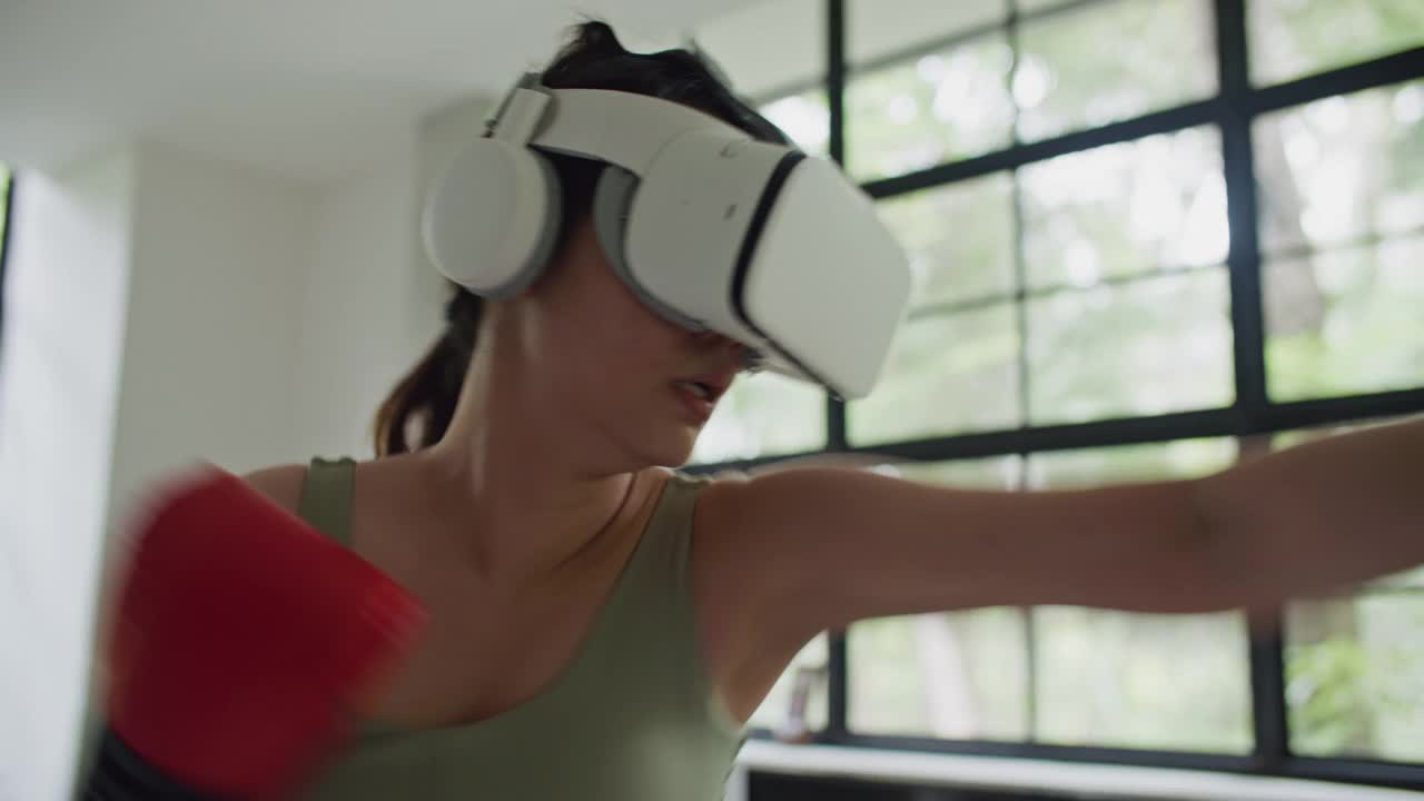体育女子拳击在虚拟现实头盔训练踢在家里虚拟现实