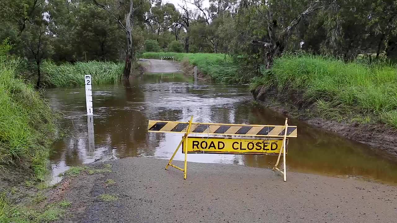 在澳大利亚农村一个被洪水淹没的小溪前，有一个道路关闭的标志