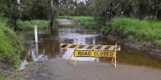 在澳大利亚农村一个被洪水淹没的小溪前，有一个道路关闭的标志